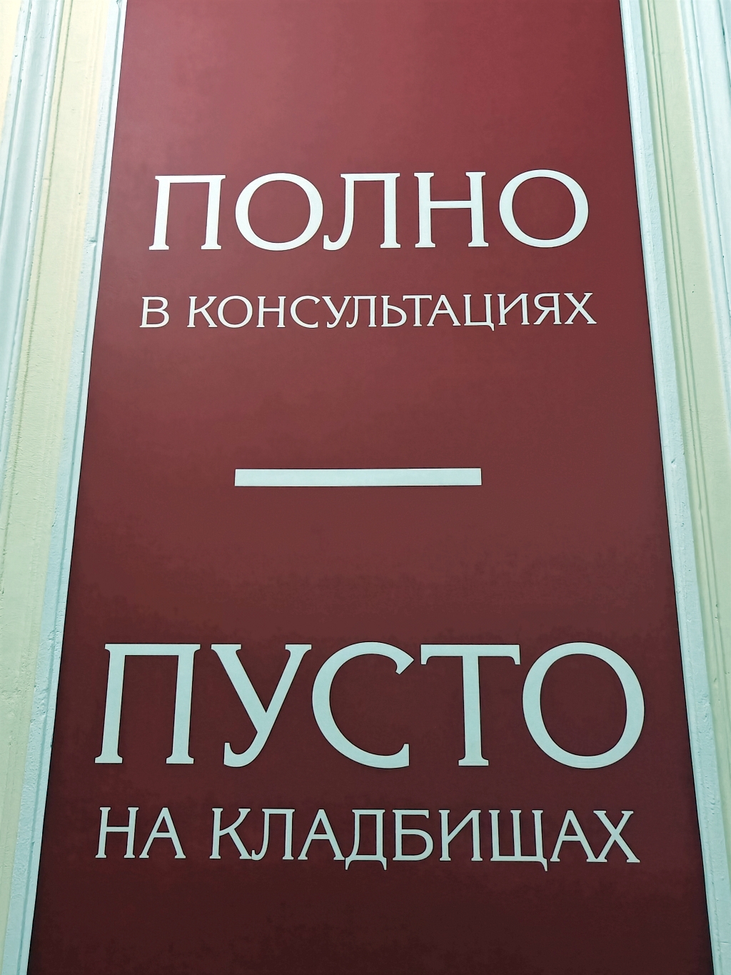 Красная вывеска с двумя фразами: «ПОЛНО в консультациях — ПУСТО на кладбищах»