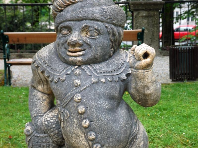 Каменная фигура в парке Зальцбурга: пузатый персонаж в шляпе и куртке с пуговицами