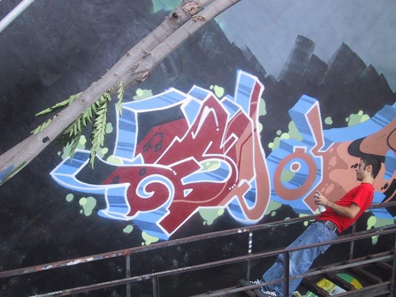 416 Grafitti Expo, Канада: художник в красной рубашке над стеной с буро-синим граffiti