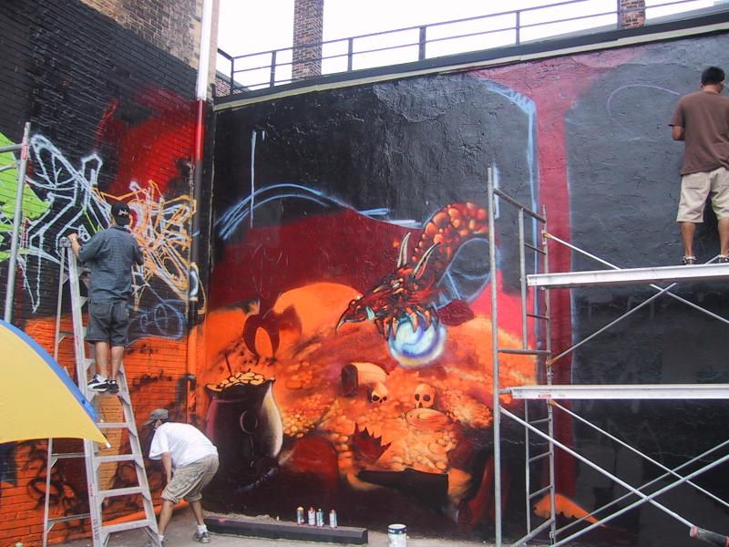 416 Grafitti Expo в Торонто: художники на лестницах и стремянках работают над муралом с крабом и золотом