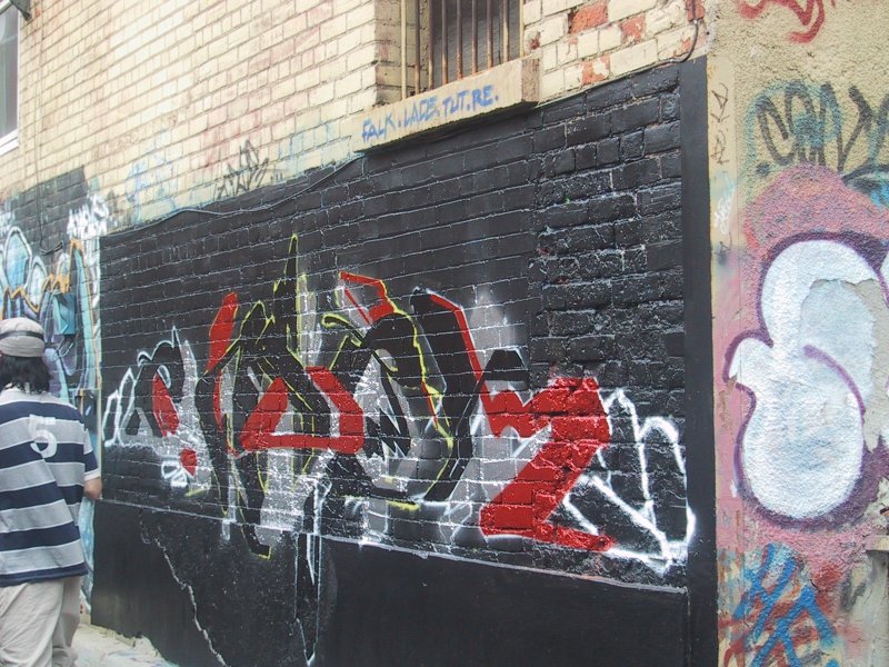 416 Grafitti Expo, Канада: чёрная стена с красно-жёлтым граффити и человеком в полосатой рубашке