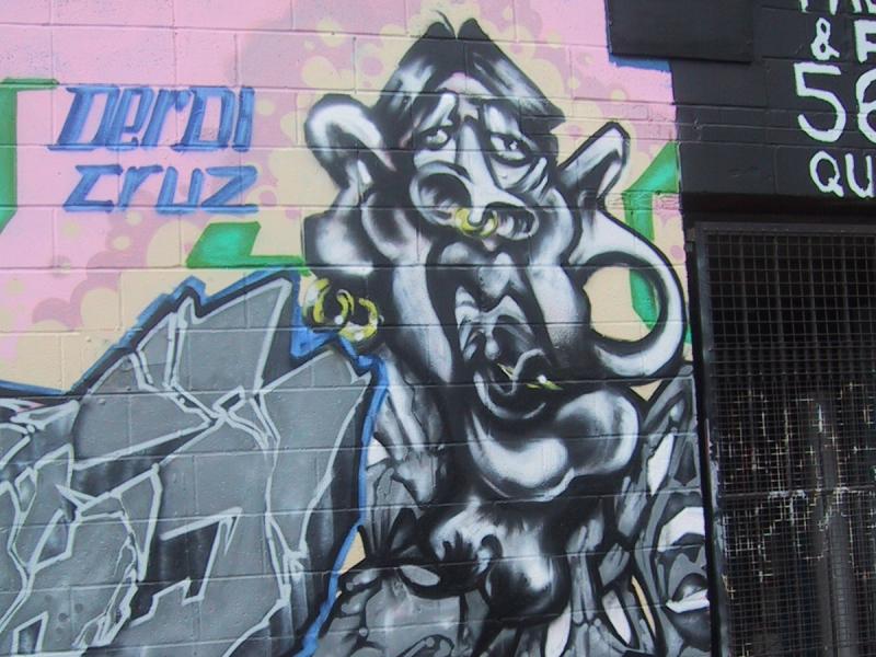 Граффити на бетонной стене с черно-белым антропоморфным персонажем и надписями