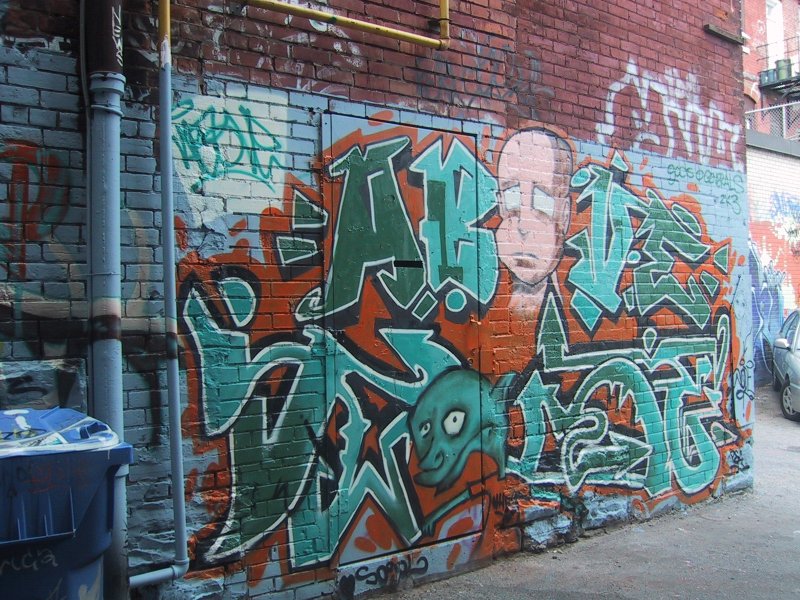 416 Grafitti Expo, Канада: кирпичная стена с зелёно-оранжевым граффити и лицом в стиле мультфильма