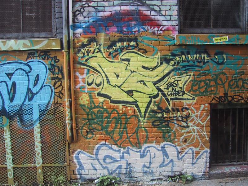 Кирпичная стена с многослойным граффити и металлическими решетками
