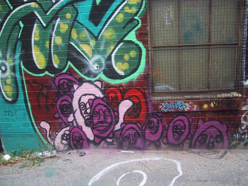 416 Grafitti Expo, Канада: зелёно-фиолетовые брызги на кирпичной стене с решёткой