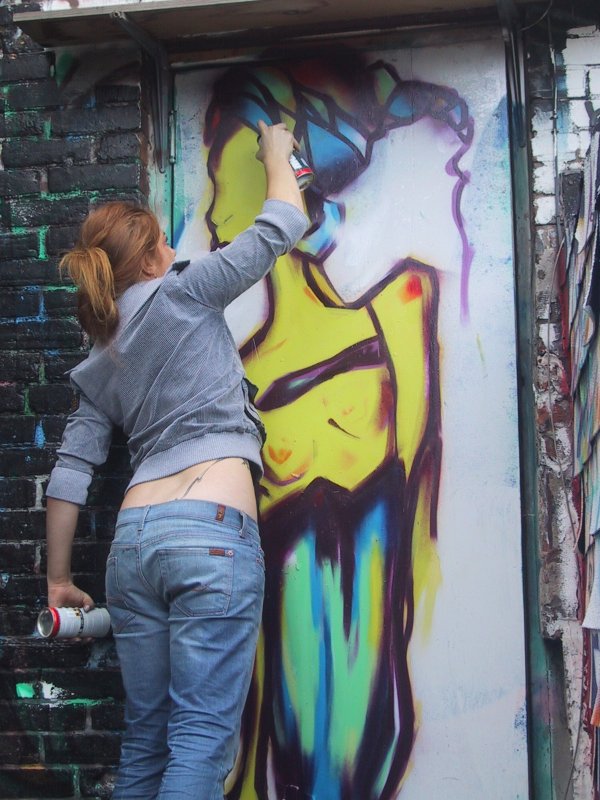 416 Graffiti Expo, Канада: женщина в серой кофте и джинсах работает над фрагментом женской фигуры в ярких тонах