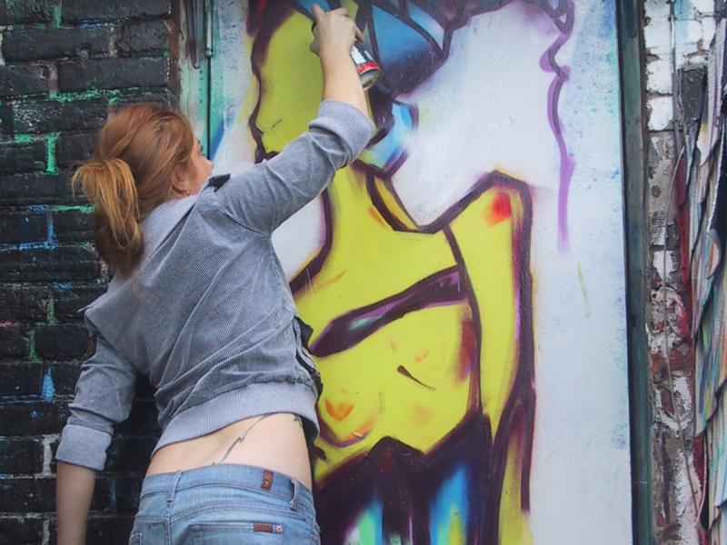 416 Graffiti Expo, Канада: женщина в серой кофте и джинсах работает над фрагментом женской фигуры в ярких тонах