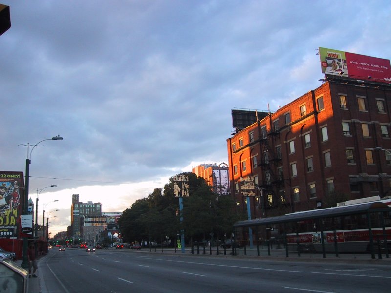 Улица в городской зоне на закате с рекламными щитами и красным кирпичным зданием