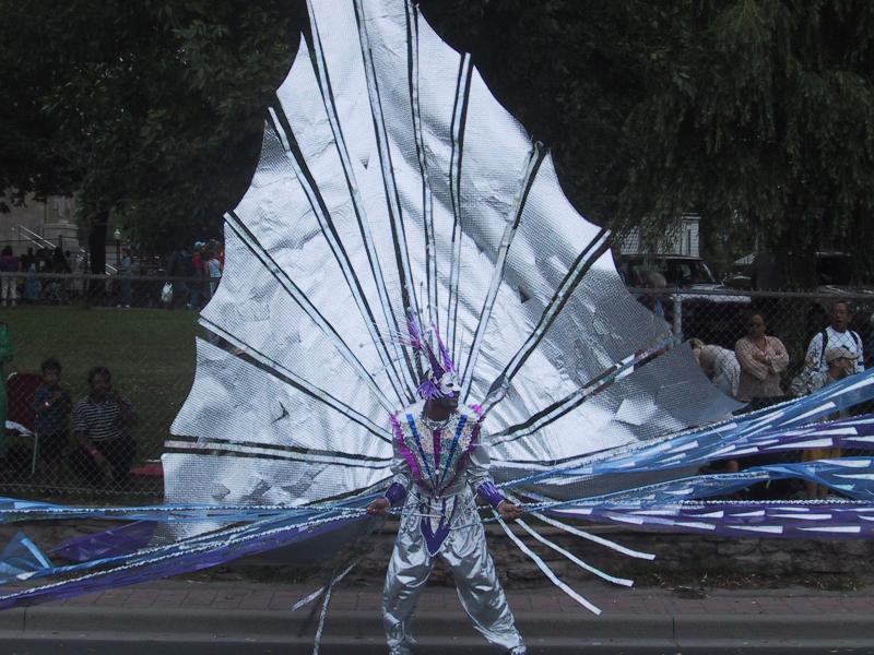 Caribana 2003 в Торонто: танцор с серебряным павлиньим хвостом и фиолетовыми лентами