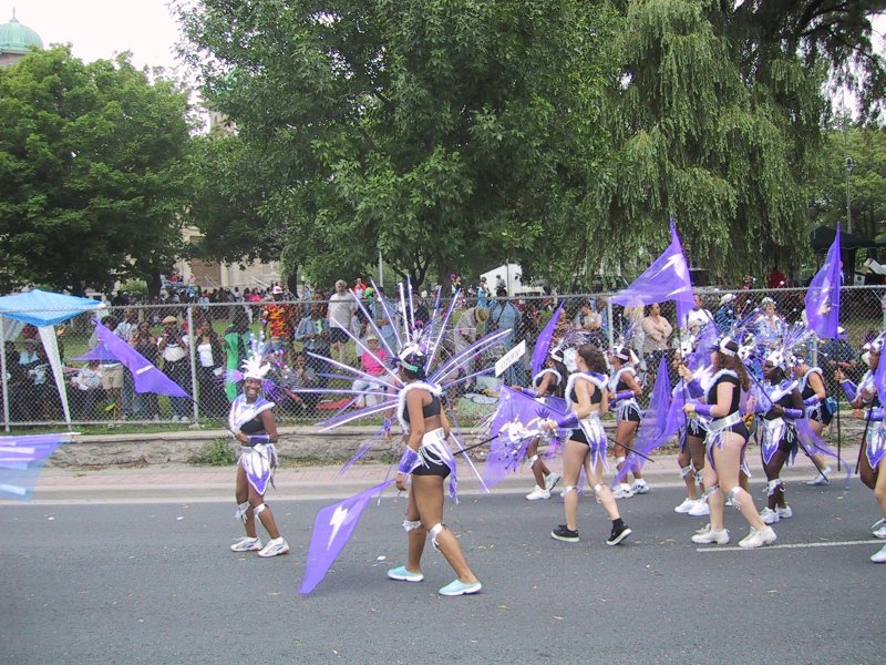 Caribana 2003 в Торонто: танцующие в фиолетовых костюмах с молниями и перьями