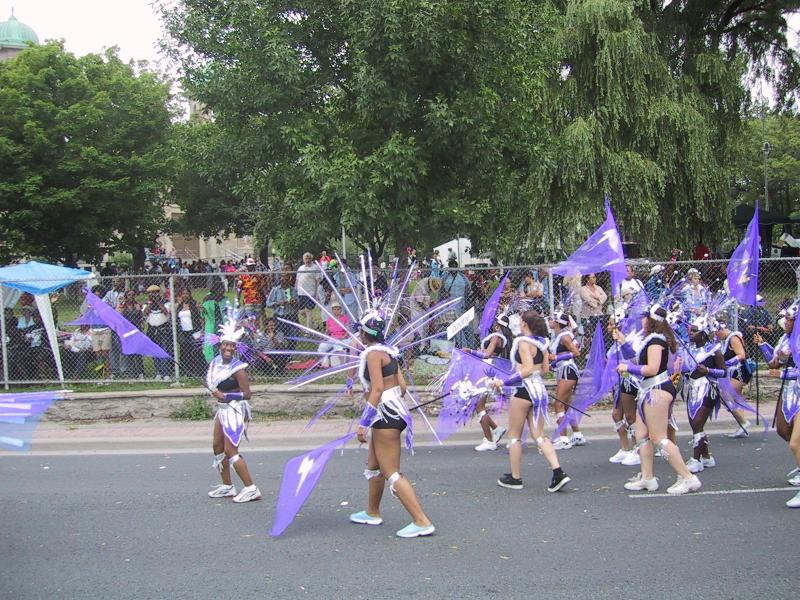 Caribana 2003 в Торонто: танцующие в фиолетовых костюмах с молниями и перьями