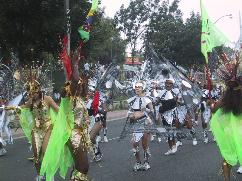 Caribana 2003 в Торонто: танцующие с флагами и перьями по улице