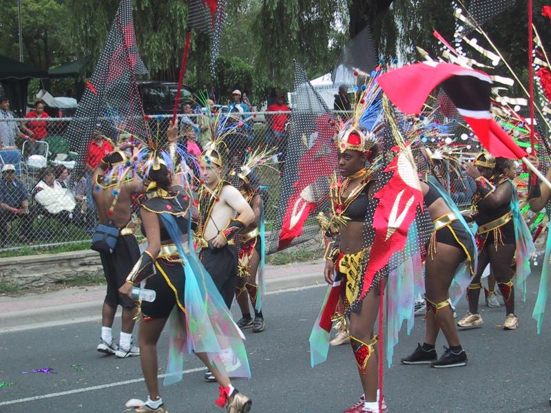 Caribana 2003 в Торонто: танцоры в пёстрой атрибутике с флагами Тринидада и Тобаго