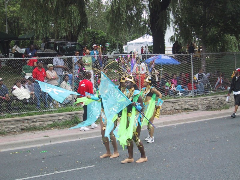 Caribana 2003 в Торонто: танцоры в зелёно-голубых костюмах с флагами и пышными головными уборами