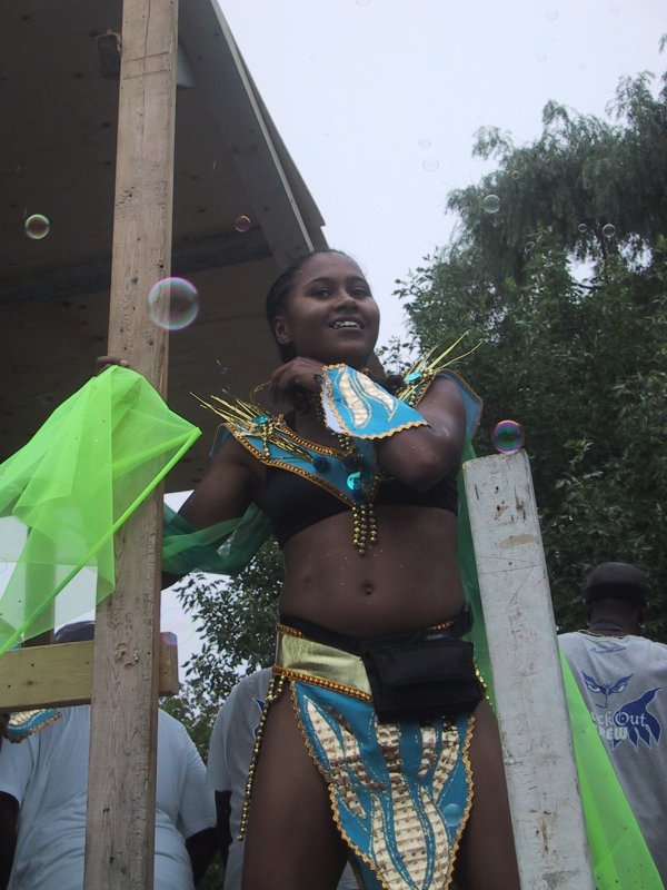Caribana 2003, Торонто: танцующая участница в сине-золотом костюме между бочками мыльных пузырей