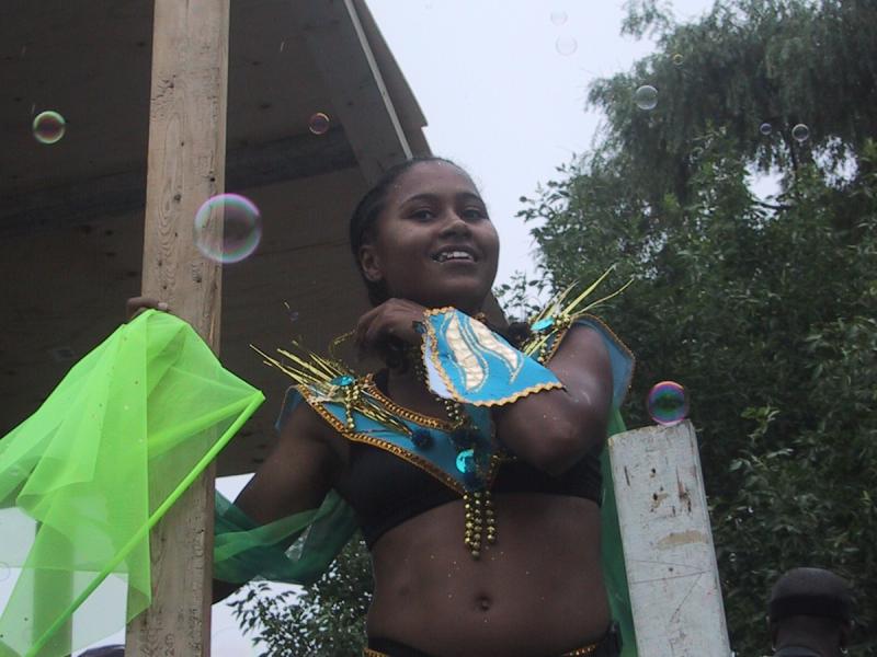 Caribana 2003, Торонто: танцующая участница в сине-золотом костюме между бочками мыльных пузырей