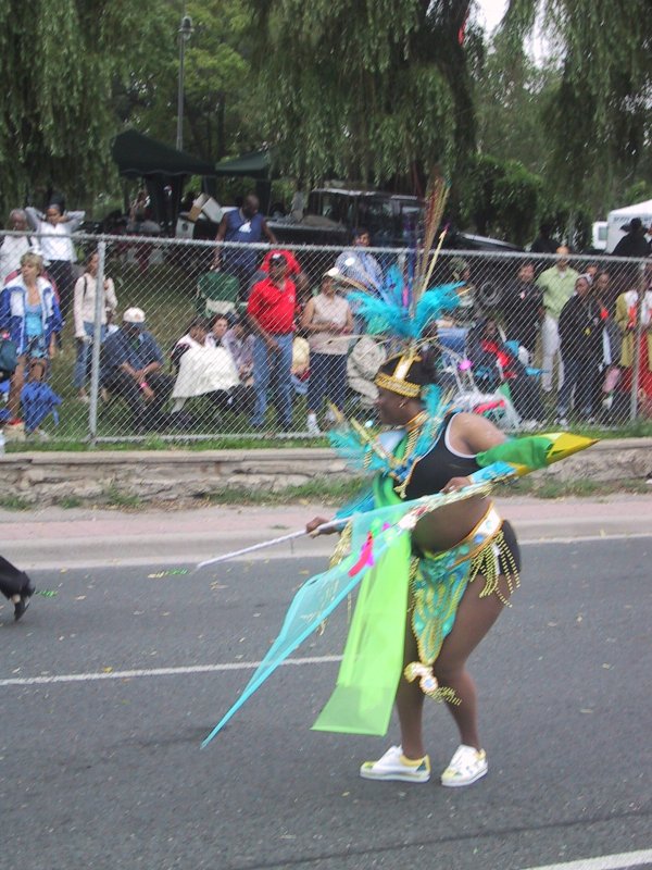 Caribana 2003 в Торонто: танцующая участница в ярком костюме с перьями и зелёными лентами