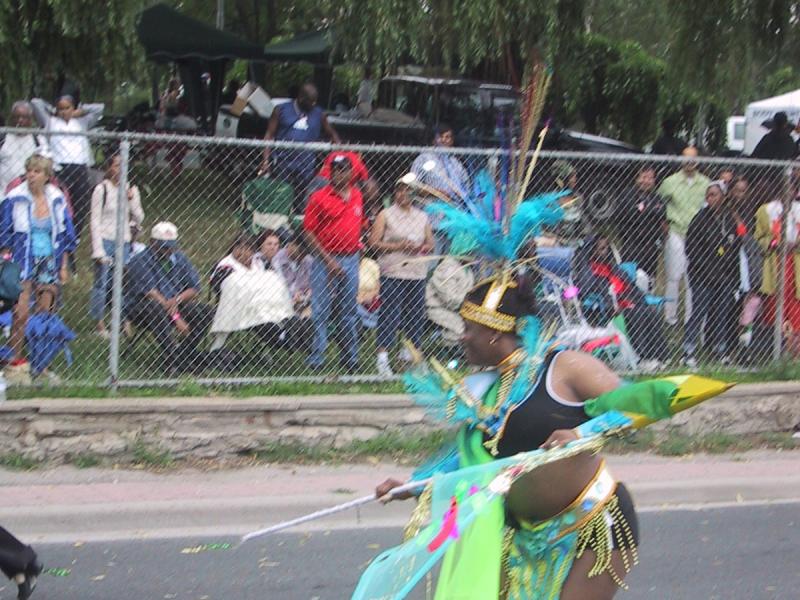 Caribana 2003 в Торонто: танцующая участница в ярком костюме с перьями и зелёными лентами