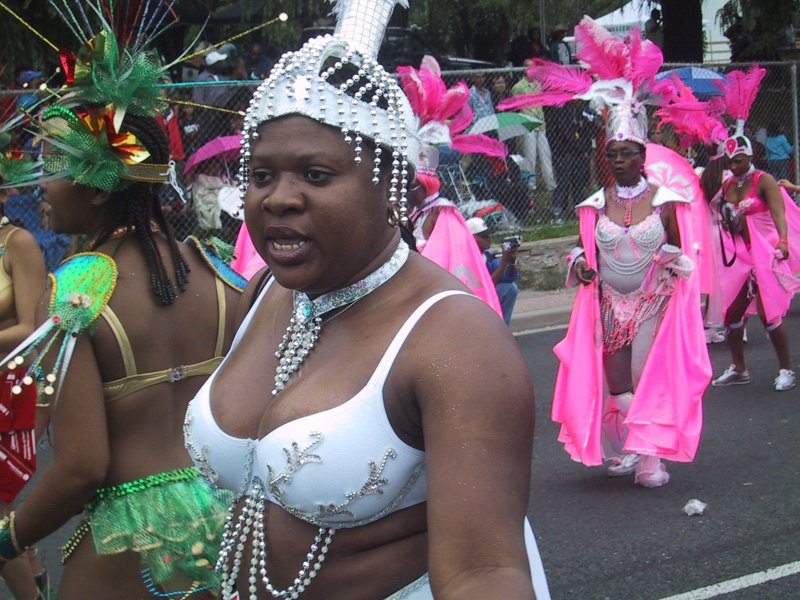 Caribana 2003 в Торонто: белоснежный костюм с жемчужинами и розовые перья на фоне ограждения