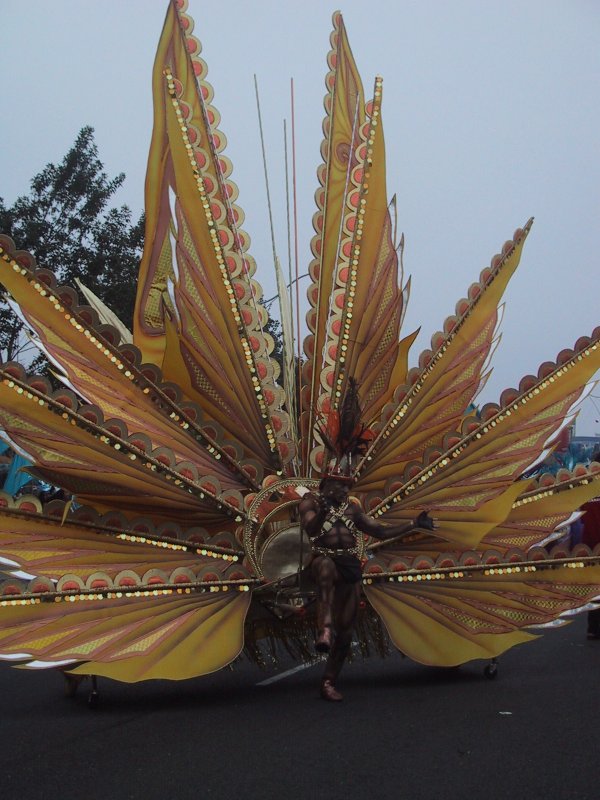 Caribana 2003 в Торонто: гигантский павлин с золотистыми перьями и бронзовым танцором