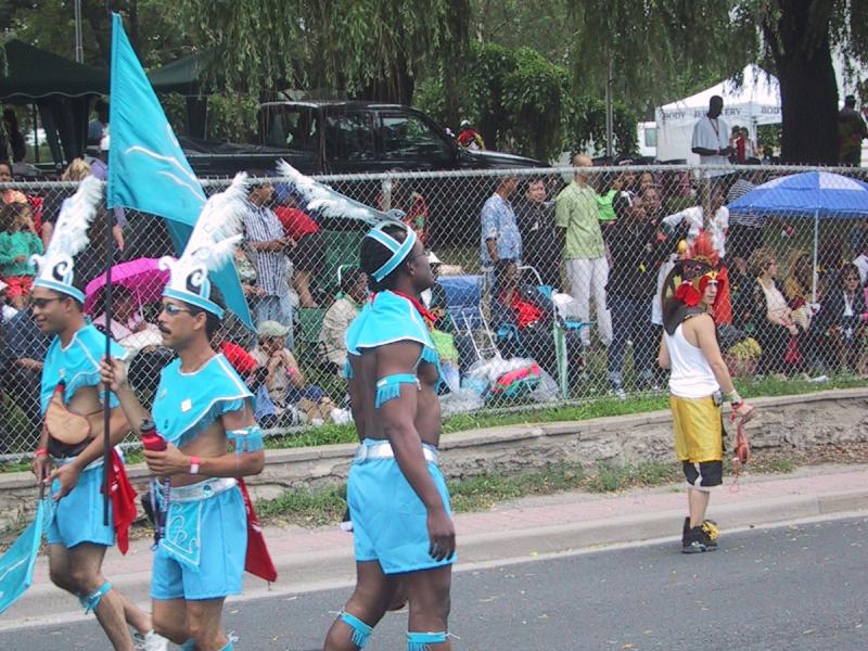 Caribana 2003 в Торонто: танцоры в голубых костюмах с перьями и флагом
