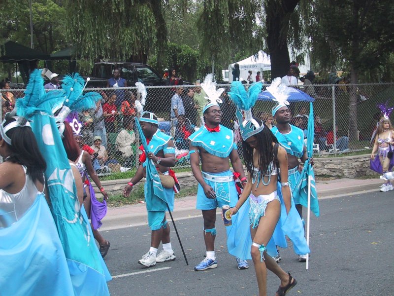 Caribana 2003 в Торонто: танцоры в бирюзовых костюмах с перьями и флагами