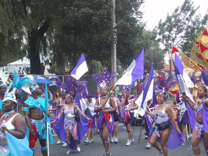 Caribana 2003 в Торонто: танцующие в фиолетово-белых костюмах с перьями и флагами
