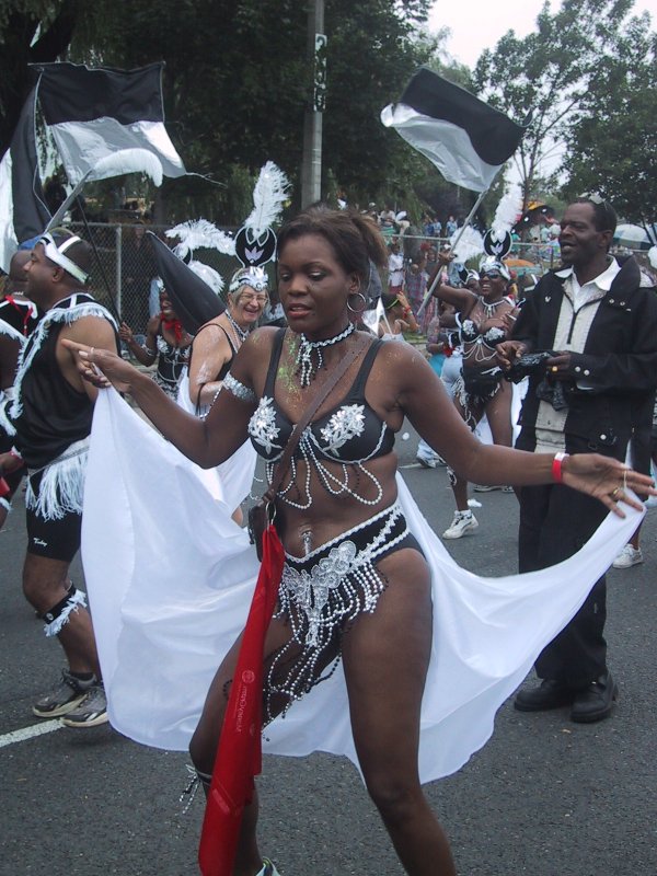 Caribana 2003 в Торонто: танцующая женщина в чёрно-белом костюме с жемчужинами и белым плащом