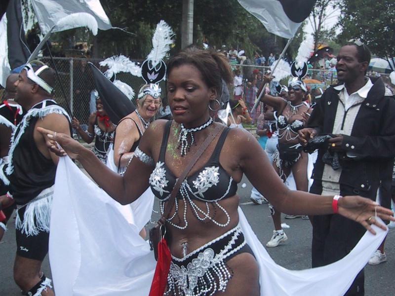 Caribana 2003 в Торонто: танцующая женщина в чёрно-белом костюме с жемчужинами и белым плащом