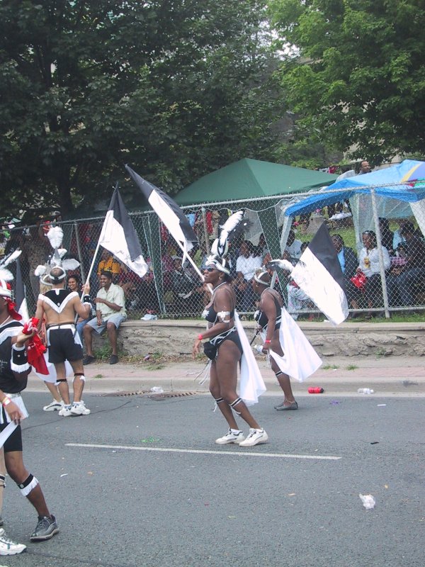 Caribana 2003 в Торонто: танцоры в чёрно-белых костюмах с перьями и флагами