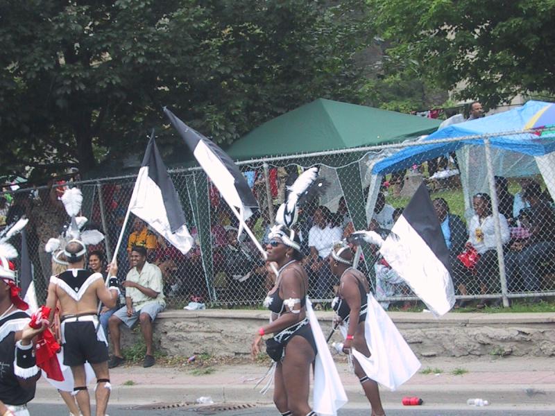 Caribana 2003 в Торонто: танцоры в чёрно-белых костюмах с перьями и флагами