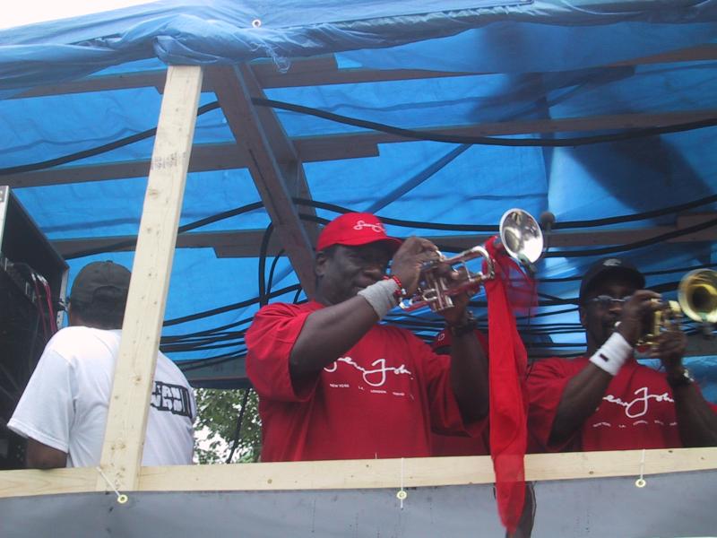 Caribana 2003, Торонто: музыканты в красных футболках с логотипом 'Jenny John' под синим навесом
