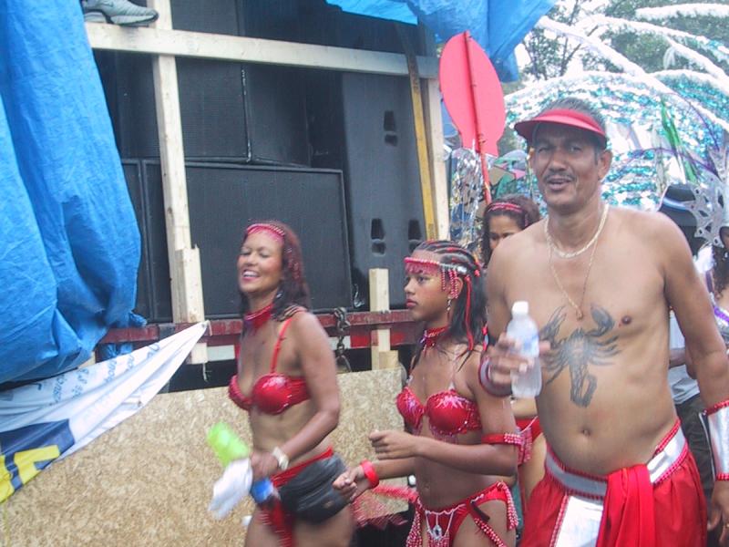 Caribana 2003 в Торонто: красные костюмы, татуированный мужчина и мокрый асфальт