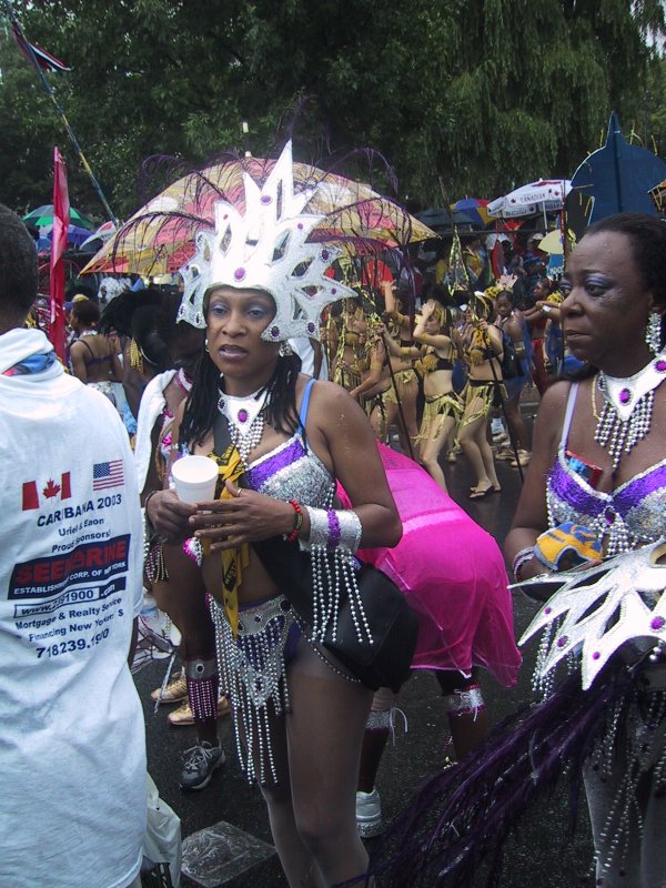 Caribana 2003 в Торонто: женщины в серебряных коронах и фиолетовых костюмах на мокрой улице