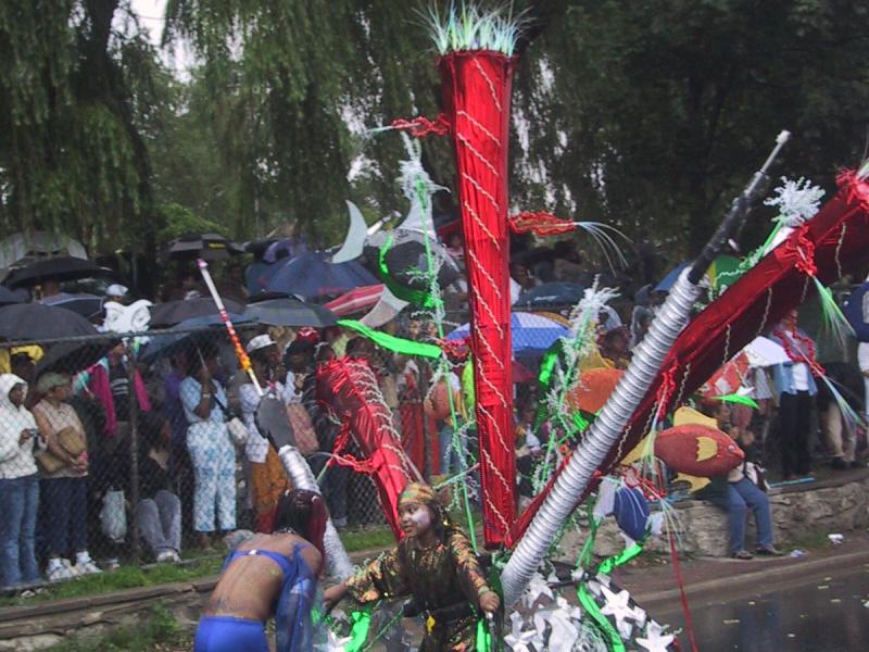 Caribana 2003 в Торонто: красный ствол с зелёными перьями и танцоры на мокрой улице
