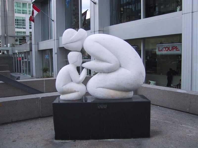 Монреаль, 2004: белая скульптура «La Tendresse» у входа в здание с флагом Канады
