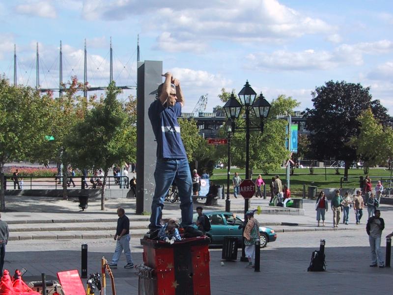 Монреаль, 2004: уличный артист на красной платформе у моста с тремя мачтами