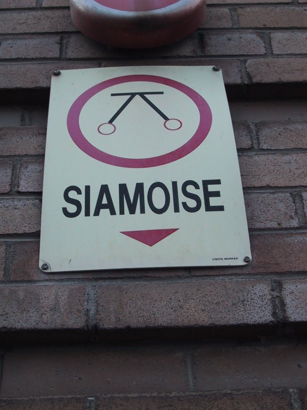 Знак с надписью 'SIAMOISE' и символом тележки на кирпичной стене
