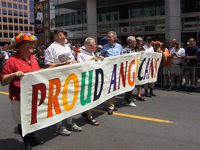 Участники гей-парада держат баннер с надписью PROUD ANGICANS