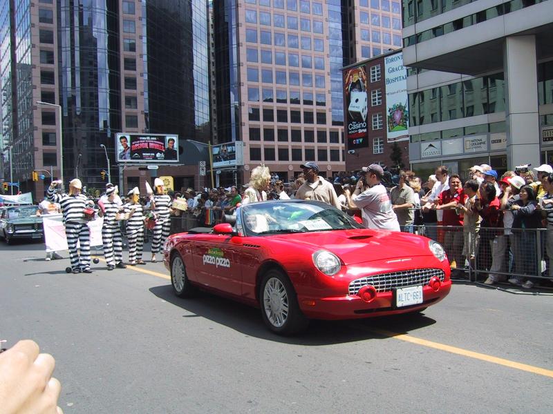 Парад гордости в Торонто, 27 июня 2004: красный Ford Thunderbird с логотипом 'Pizza Pizza' и тюремными костюмами