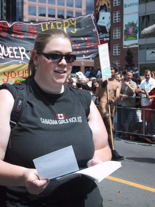Парад гордости в Канаде, 27 июня 2004: женщина в футболке «Canadian Girls Kick Ass» с листовками