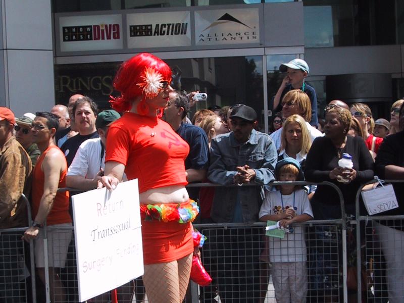 Парад гордости в Канаде, 27 июня 2004: красная фигура с табличкой «Return Transsexual Surgery Funding»