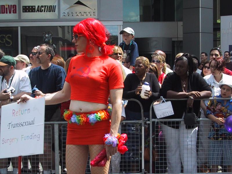 Парад гордости в Торонто, 27 июня 2004: красная фигура с табличкой «Return Transsexual Surgery Funding»