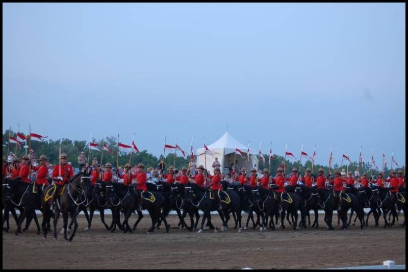 Парад конных рядах RCMP в Канаде: красные мундиры и флаги над пыльной ареной