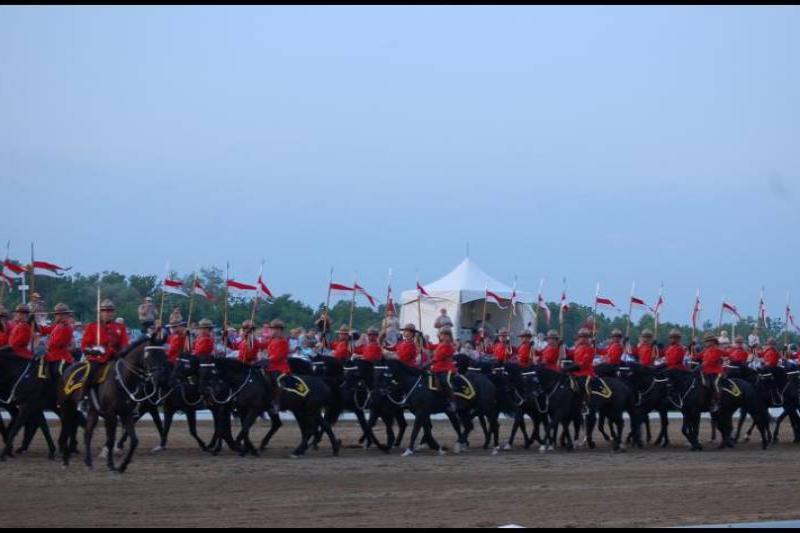 Парад конных рядах RCMP в Канаде: красные мундиры и флаги над пыльной ареной
