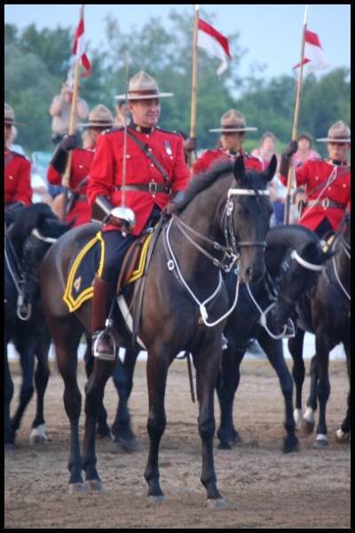 RCMP в красных мундирах на конях у флагов в Канаде