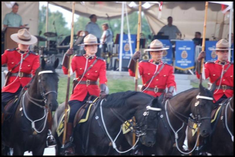 RCMP в красных мундирах на конях у палатки с эмблемой Королевской канадской полиции