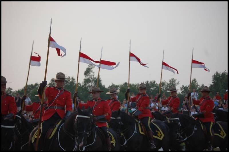 RCMP в красных мундирах на конях с флагами в Канаде