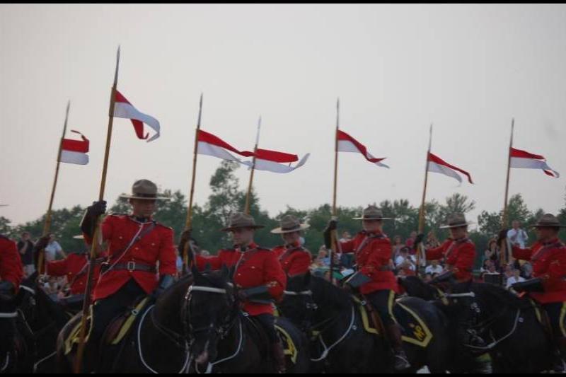RCMP в красных мундирах на конях с флагами в Канаде