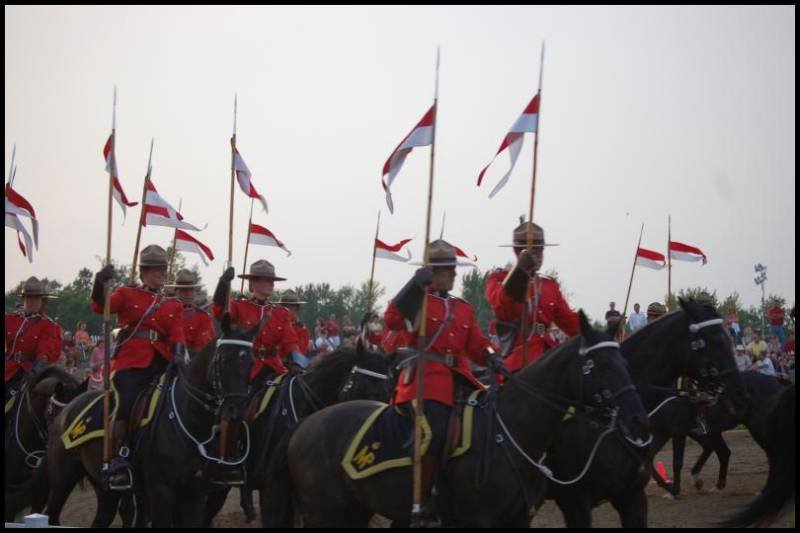 RCMP в красных мундирах на конях с флагами в Канаде